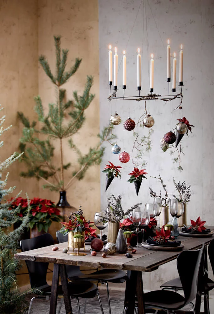 Ένα απλό ξύλινο τραπέζι αποχτά γιορτινό χαρακτήρα με λίγα φυτά και ανθισμένους βλαστούς από κόκκινο αλεξανδρινό. 
